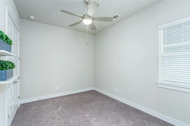 an empty room with a window and a fan