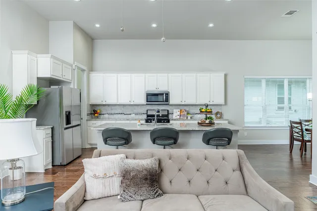 a living room with furniture and a dining table with wooden floor