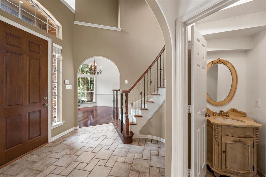 5607 Ranger Drive Rockwall, TX 75032 - Photo 8 of 40 Two-story foyer featuring tile flooring, a wood front door with sidelights, and a staircase with wood treads and wrought iron balusters