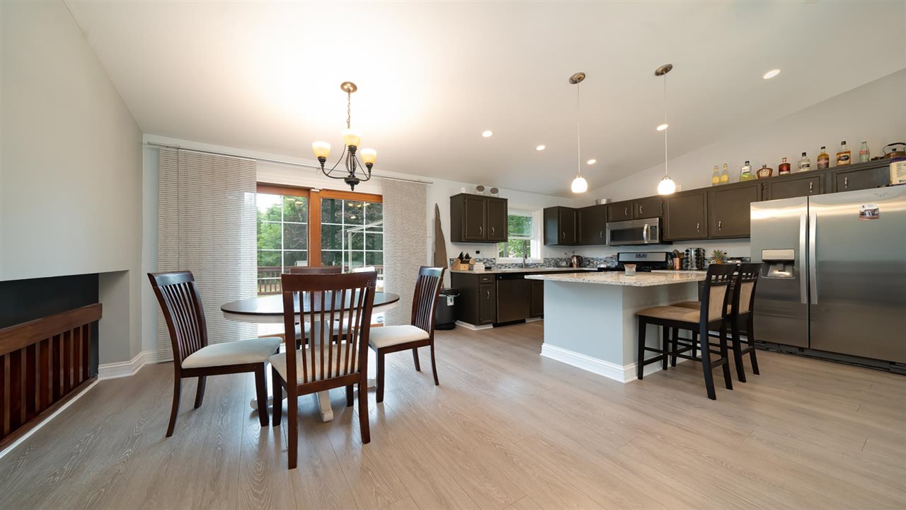 310 Pembroke Road Southwest Poplar Grove, IL 61065 - Photo 7 of 27 a kitchen with stainless steel appliances kitchen island granite countertop a dining table chairs stove a refrigerator and a window