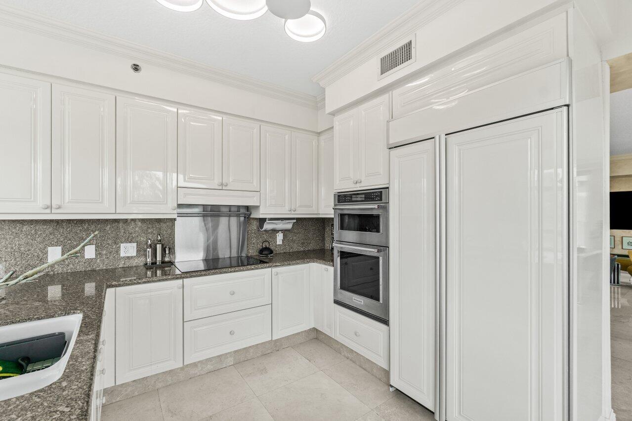 3740 South Ocean Boulevard, Unit 201 Highland Beach, FL 33487 - Photo 13 of 62 a kitchen with white cabinets and white appliances