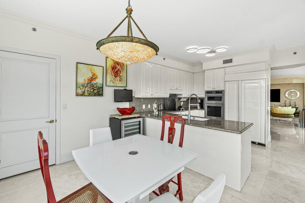 3740 South Ocean Boulevard, Unit 201 Highland Beach, FL 33487 - Photo 15 of 62 a kitchen with stainless steel appliances kitchen island granite countertop a refrigerator a stove a sink dishwasher and white cabinets with wooden floor