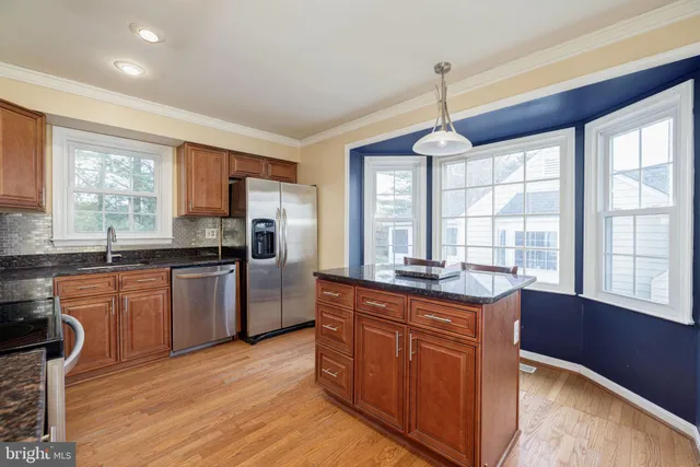a kitchen with granite countertop wooden floors appliances and window