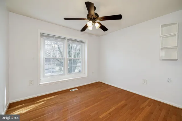 a view of empty room with wooden floor and window