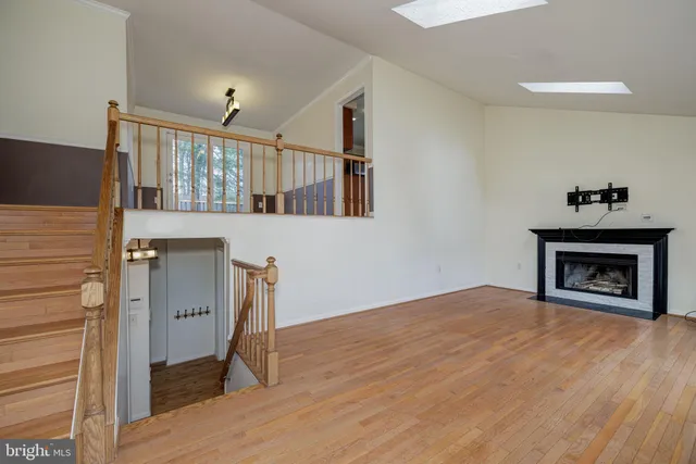 a view of an empty room with wooden floor fireplace and a window