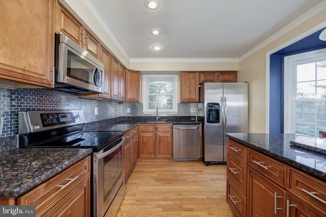 a kitchen with stainless steel appliances granite countertop a refrigerator a stove a sink and a microwave