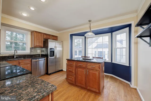 a kitchen with granite countertop a stove top oven a sink dishwasher a dining table and chairs with wooden floor