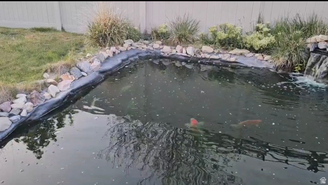 592 West 650 South Springville, UT 84663 - Photo 25 of 33 Backyard pond featuring a rock-lined edge, integrated waterfall, and surrounding landscaping with mature grasses