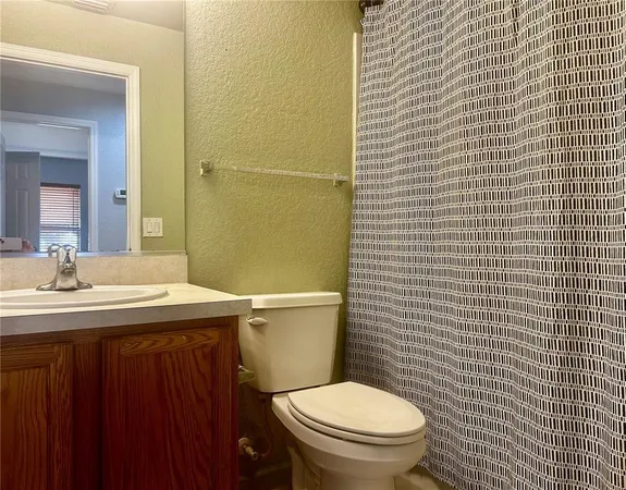 a bathroom with a granite countertop toilet a sink and a mirror