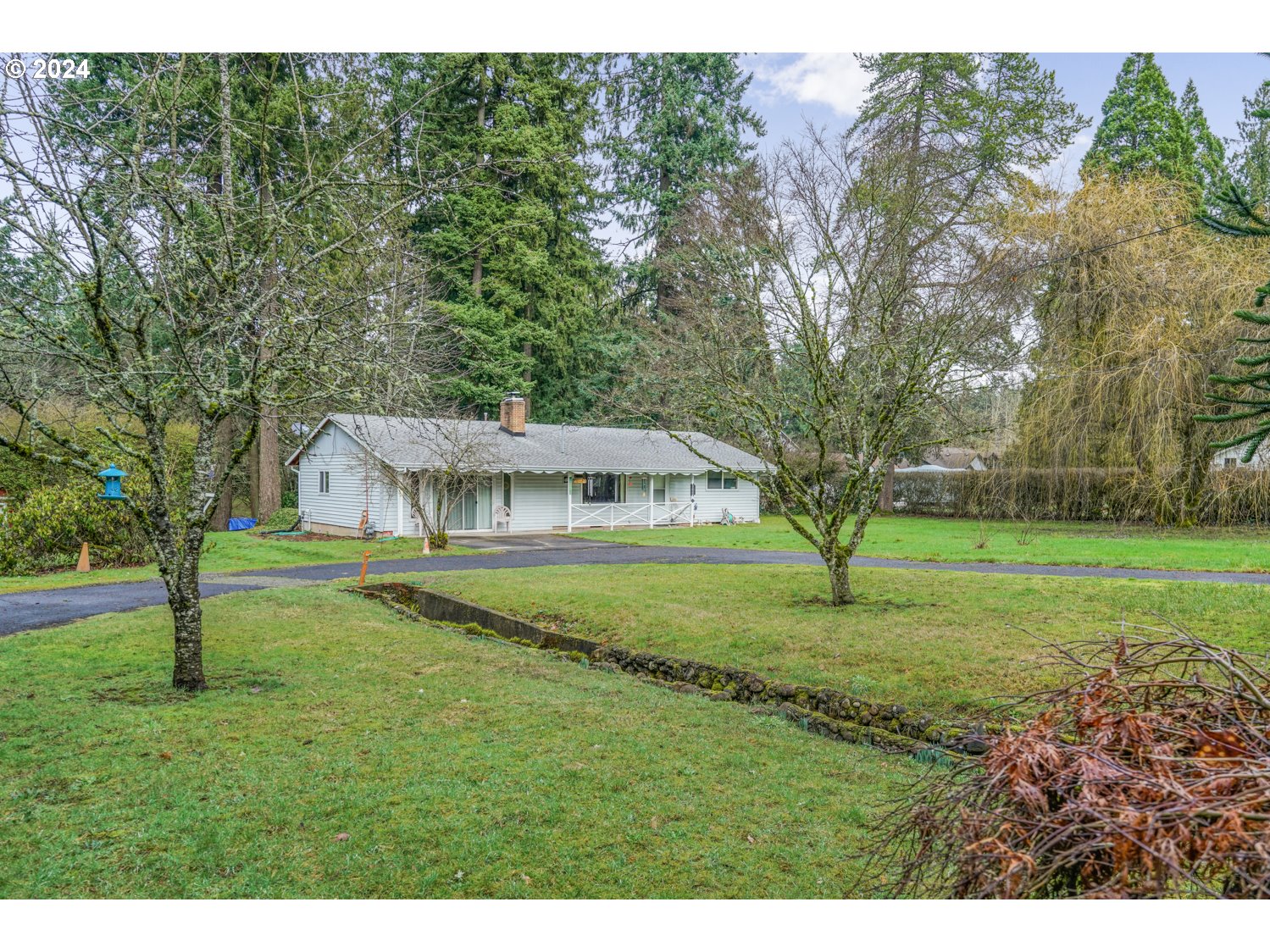 a view of a house with big yard and large trees