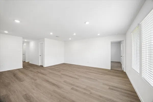 a view of an empty room with wooden floor and a window