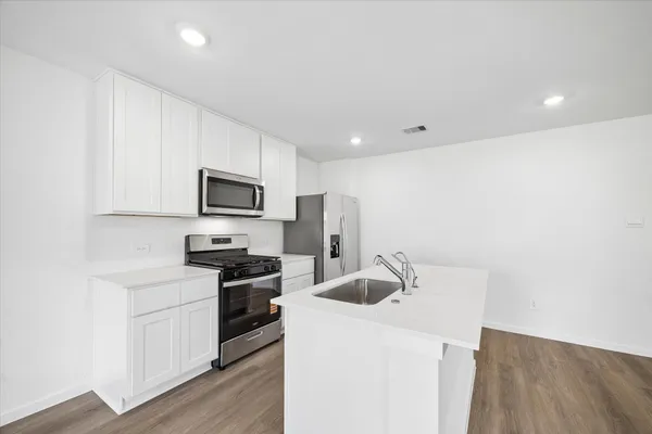 a kitchen with a sink a stove top oven and white stainless steel appliances