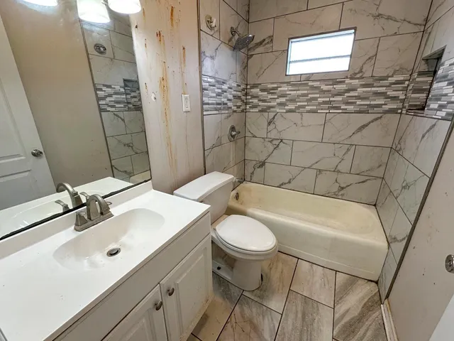 a bathroom with a sink and mirror with bathtub
