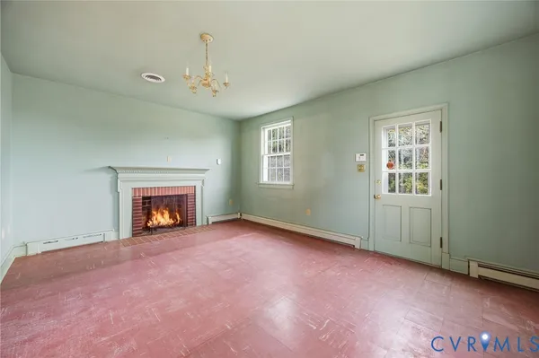 an empty room with windows and fireplace