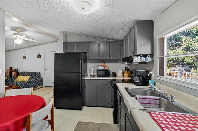 a kitchen with a refrigerator a stove a sink dishwasher and a dining table with wooden floor