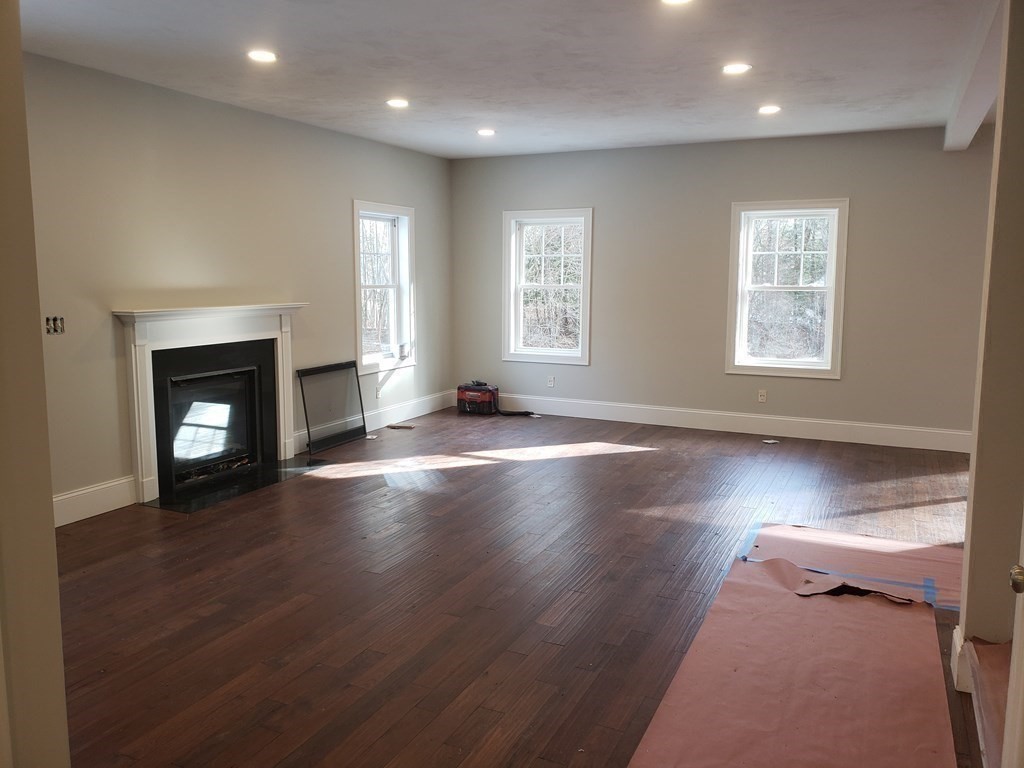 166 Pepperell Road Groton, MA 01450 - Photo 11 of 22 an empty room with wooden floor fireplace and windows