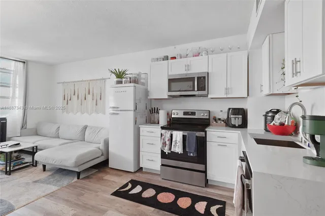 a white kitchen with white cabinets and stainless steel appliances