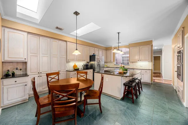 a kitchen with a dining table chairs and white cabinets