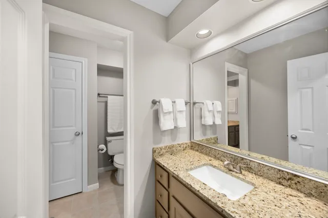 a bathroom with a granite countertop sink mirror and a toilet
