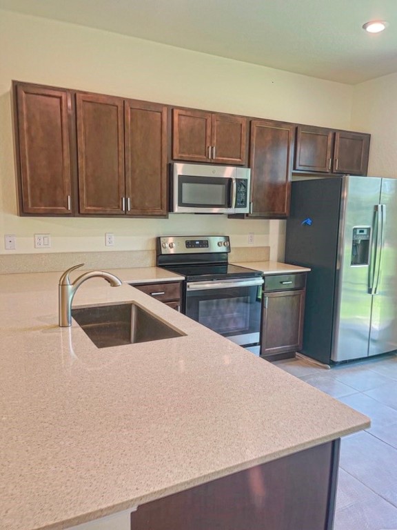 a kitchen with stainless steel appliances a refrigerator a sink a stove a microwave and wooden cabinets