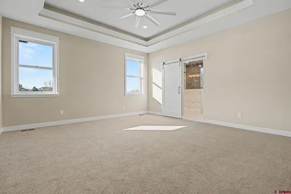 an empty room with windows and ceiling fan