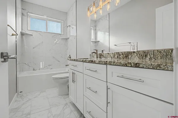 a bathroom with a granite countertop sink mirror toilet and bathtub