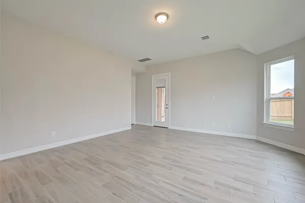 a view of an empty room with wooden floor and window