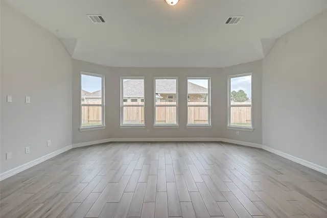 an empty room with wooden floor and windows