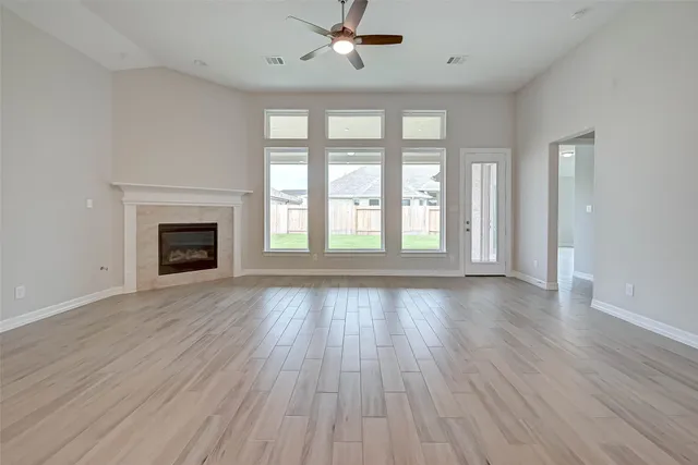 an empty room with wooden floor fireplace and windows
