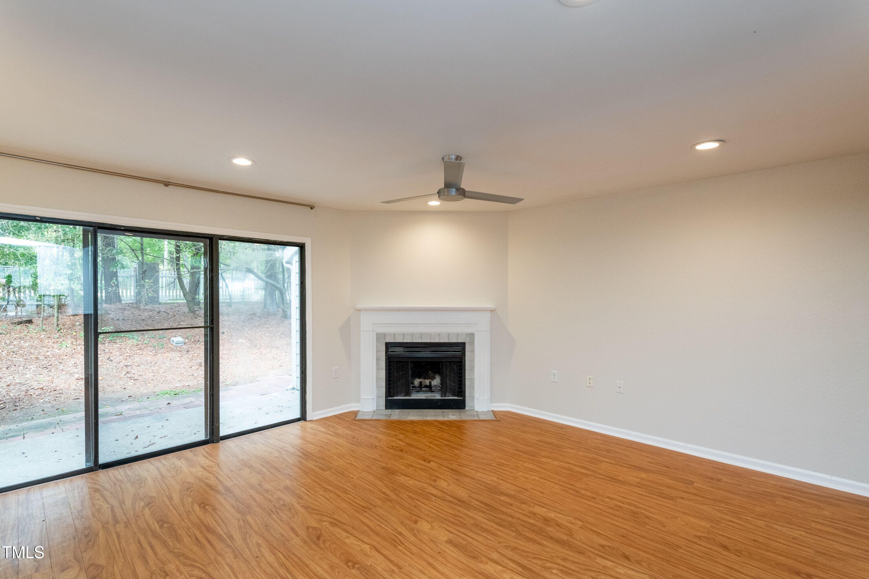 2434 Condor Court Raleigh, NC 27615 - Photo 11 of 21 a view of an empty room with wooden floor fireplace and a window