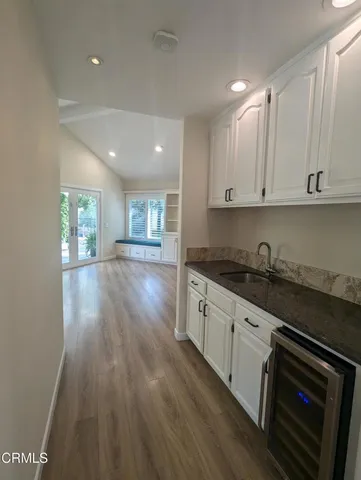 a kitchen with granite countertop a stove top oven a sink and white cabinets with wooden floor