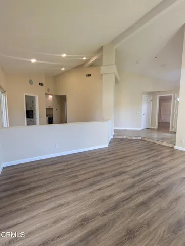 a view of a big room with wooden floor and windows