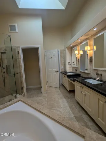 a large bathroom with a granite countertop sink two mirror and a shower