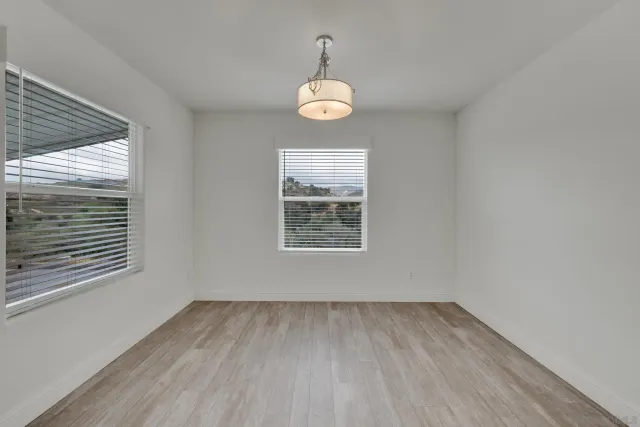 an empty room with windows and ceiling fan