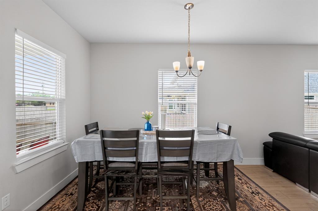 411 West Harwood Road Euless, TX 76039 - Photo 11 of 29 Dining area featuring a contemporary chandelier, a window with blinds, and light-colored walls