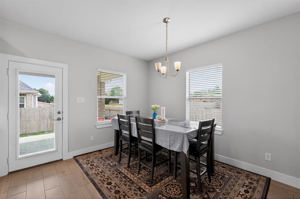 411 West Harwood Road Euless, TX 76039 - Photo 12 of 29 Dining area with light gray walls, a modern chandelier, and two windows providing natural light