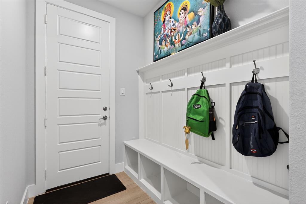 411 West Harwood Road Euless, TX 76039 - Photo 13 of 29 Entryway featuring a white paneled door, light-colored flooring, and a white built-in storage bench with hooks