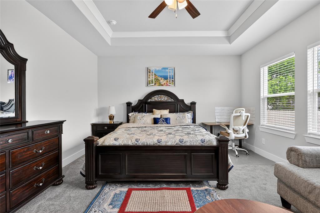 411 West Harwood Road Euless, TX 76039 - Photo 14 of 29 This room features a tray ceiling with a ceiling fan, two windows with blinds, and carpeting