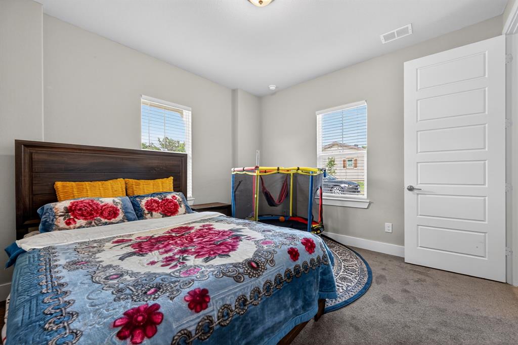 411 West Harwood Road Euless, TX 76039 - Photo 19 of 29 This room features carpeted flooring, a dark wood headboard, and two windows providing natural light