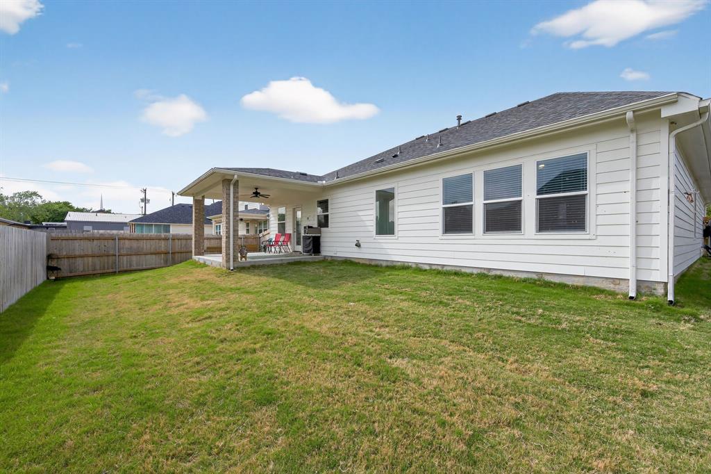 411 West Harwood Road Euless, TX 76039 - Photo 29 of 29 The property features a spacious backyard with a lawn, a covered patio, and a privacy fence