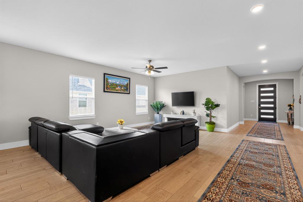 411 West Harwood Road Euless, TX 76039 - Photo 4 of 29 The open concept living area features light wood flooring, recessed lighting, and a ceiling fan