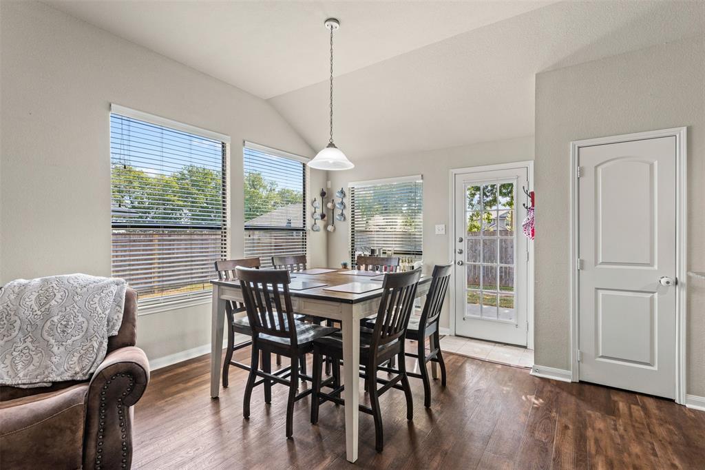 10313 Condor Loop Waco, TX 76708 - Photo 14 of 33 Vaulted ceiling with a pendant light fixture, wood-finish flooring, multiple windows with blinds, and a paneled door