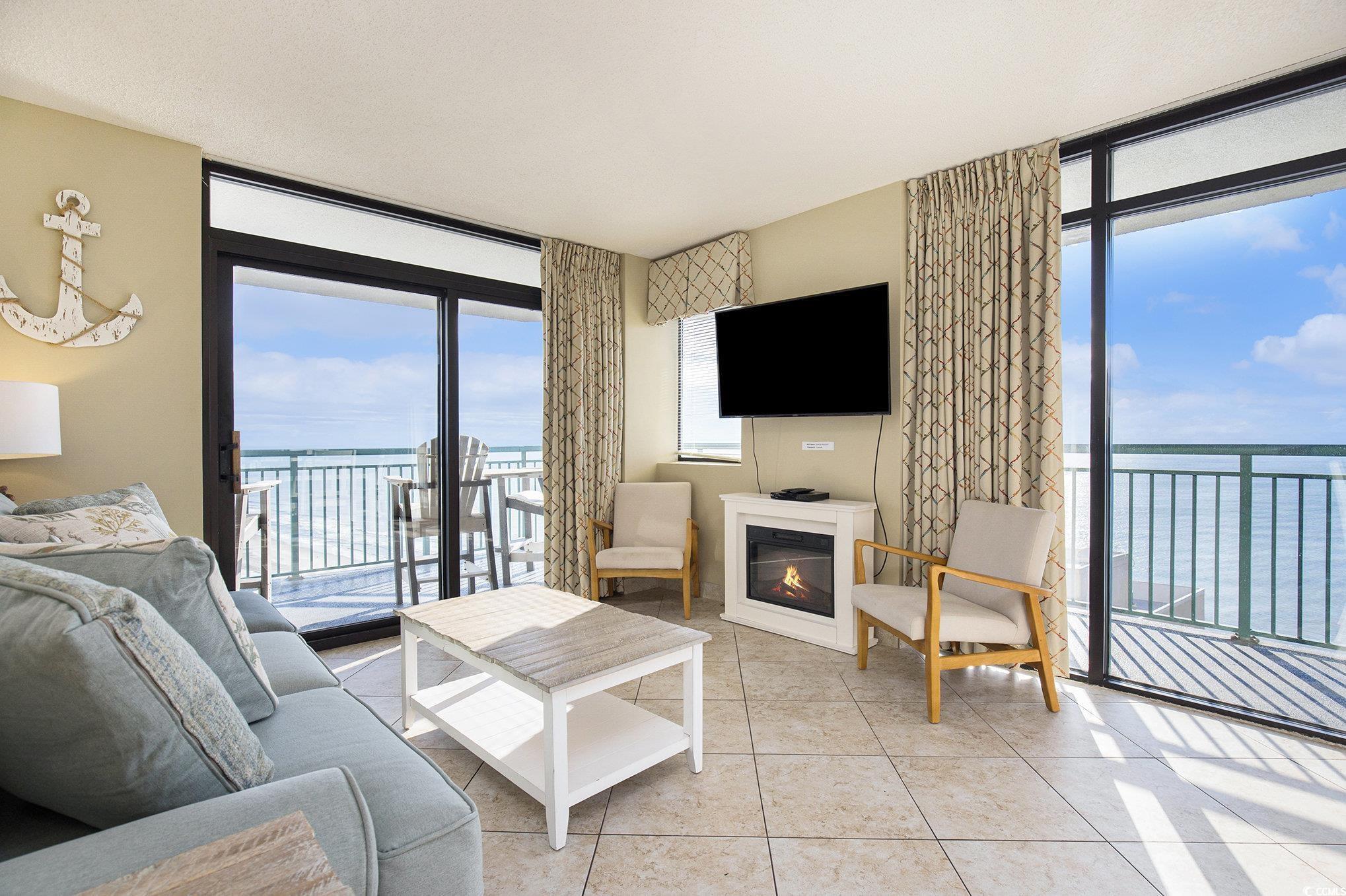 205 74th Avenue North, Unit 1810 Myrtle Beach, SC 29572 - Photo 19 of 37 Living area featuring a wall of windows, light tile patterned floors, and a glass covered fireplace