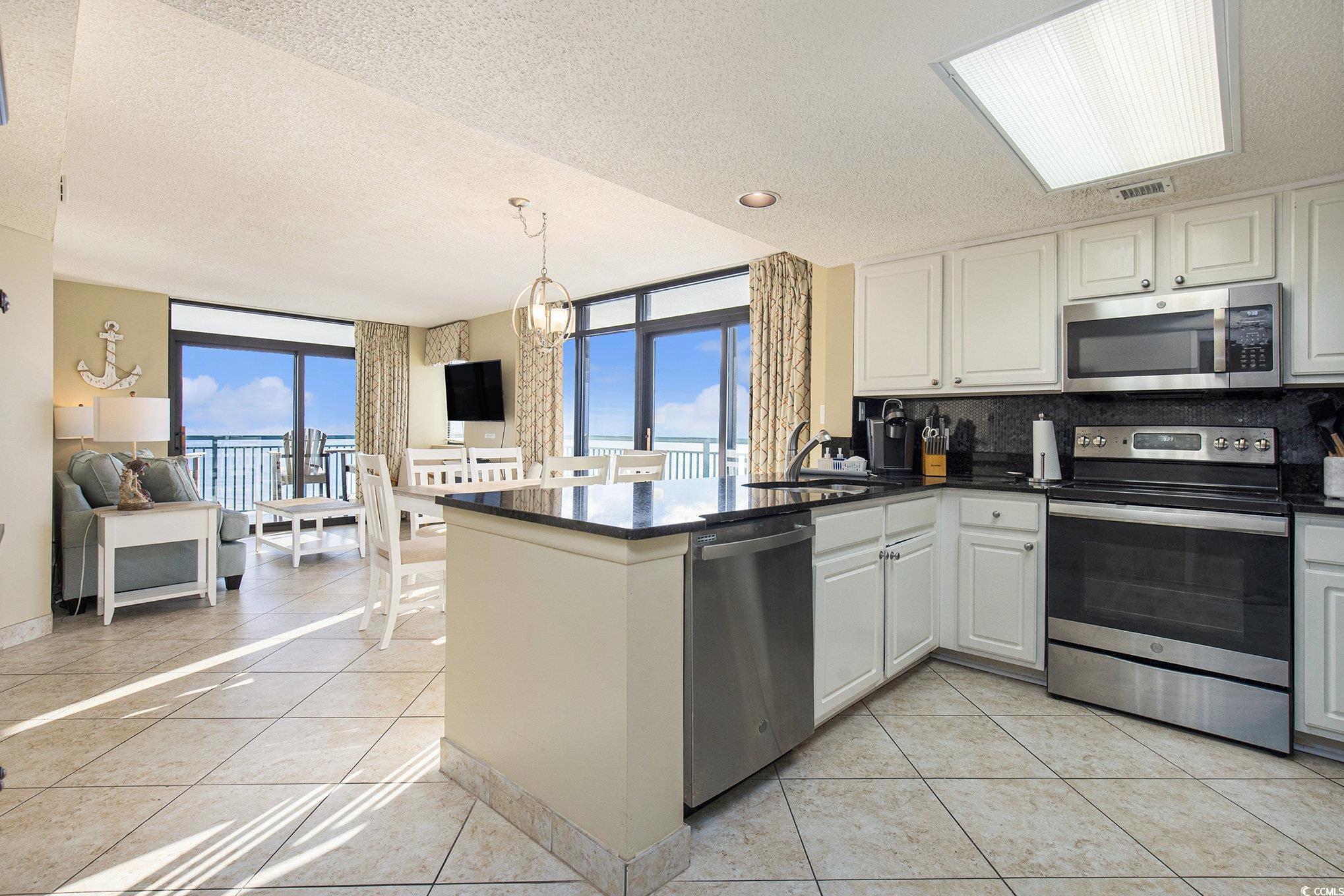 205 74th Avenue North, Unit 1810 Myrtle Beach, SC 29572 - Photo 22 of 37 Kitchen with a textured ceiling, appliances with stainless steel finishes, light tile patterned floors, tasteful backsplash, and a wall of windows