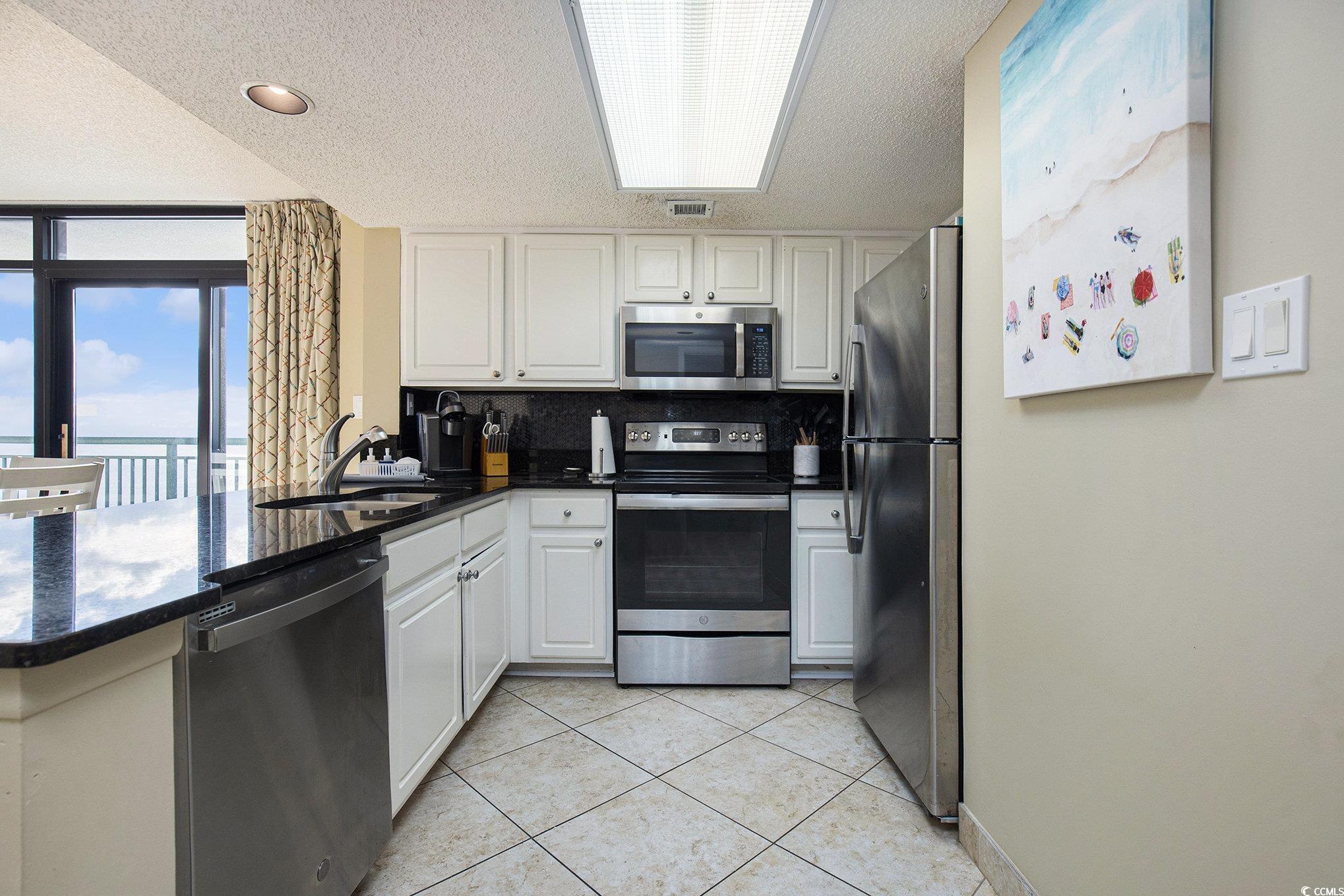 205 74th Avenue North, Unit 1810 Myrtle Beach, SC 29572 - Photo 23 of 37 Kitchen with stainless steel appliances, white cabinets, decorative backsplash, dark stone counters, and a peninsula