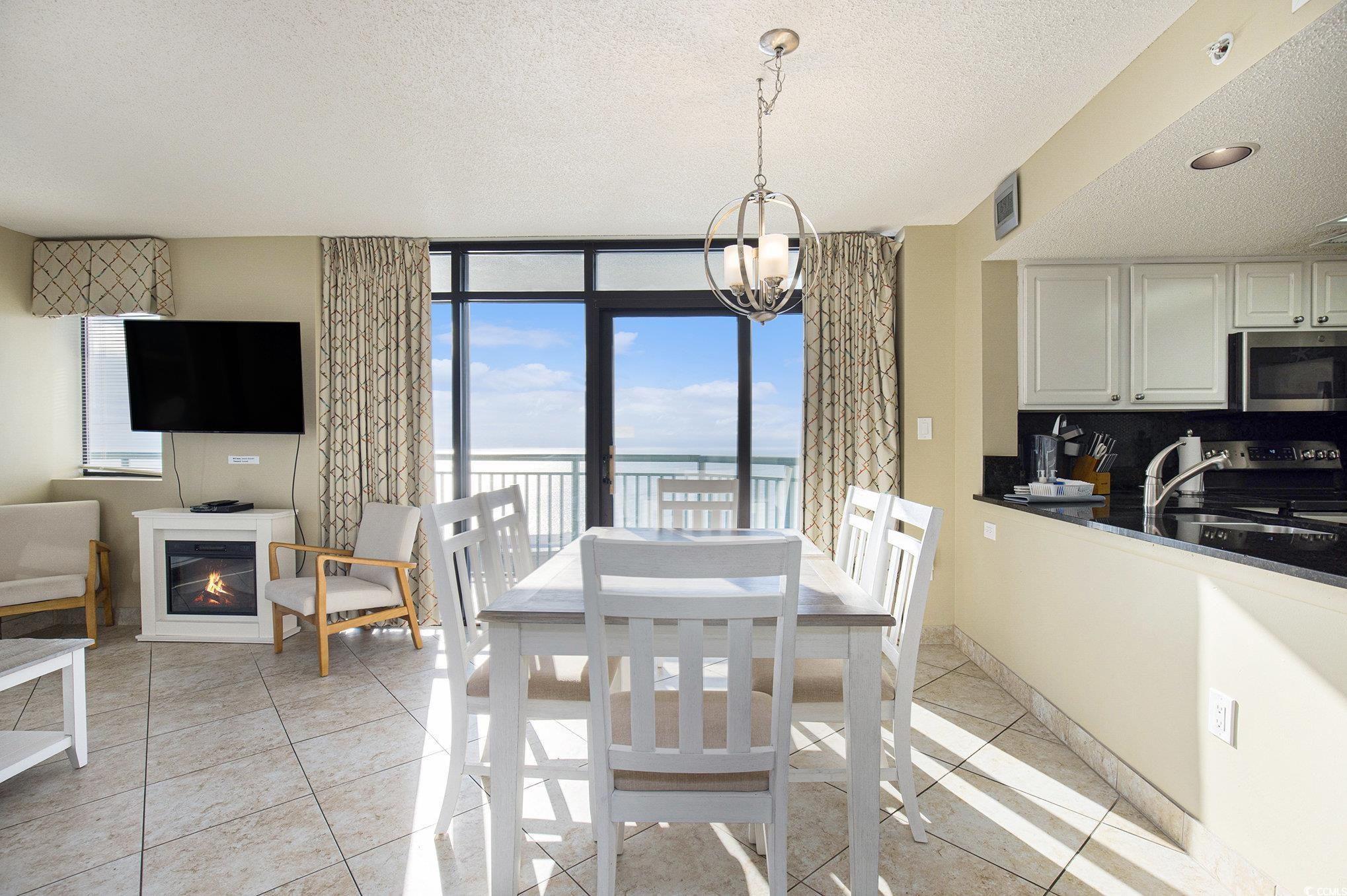 205 74th Avenue North, Unit 1810 Myrtle Beach, SC 29572 - Photo 24 of 37 Dining area featuring a textured ceiling, light tile patterned flooring, expansive windows, and a chandelier