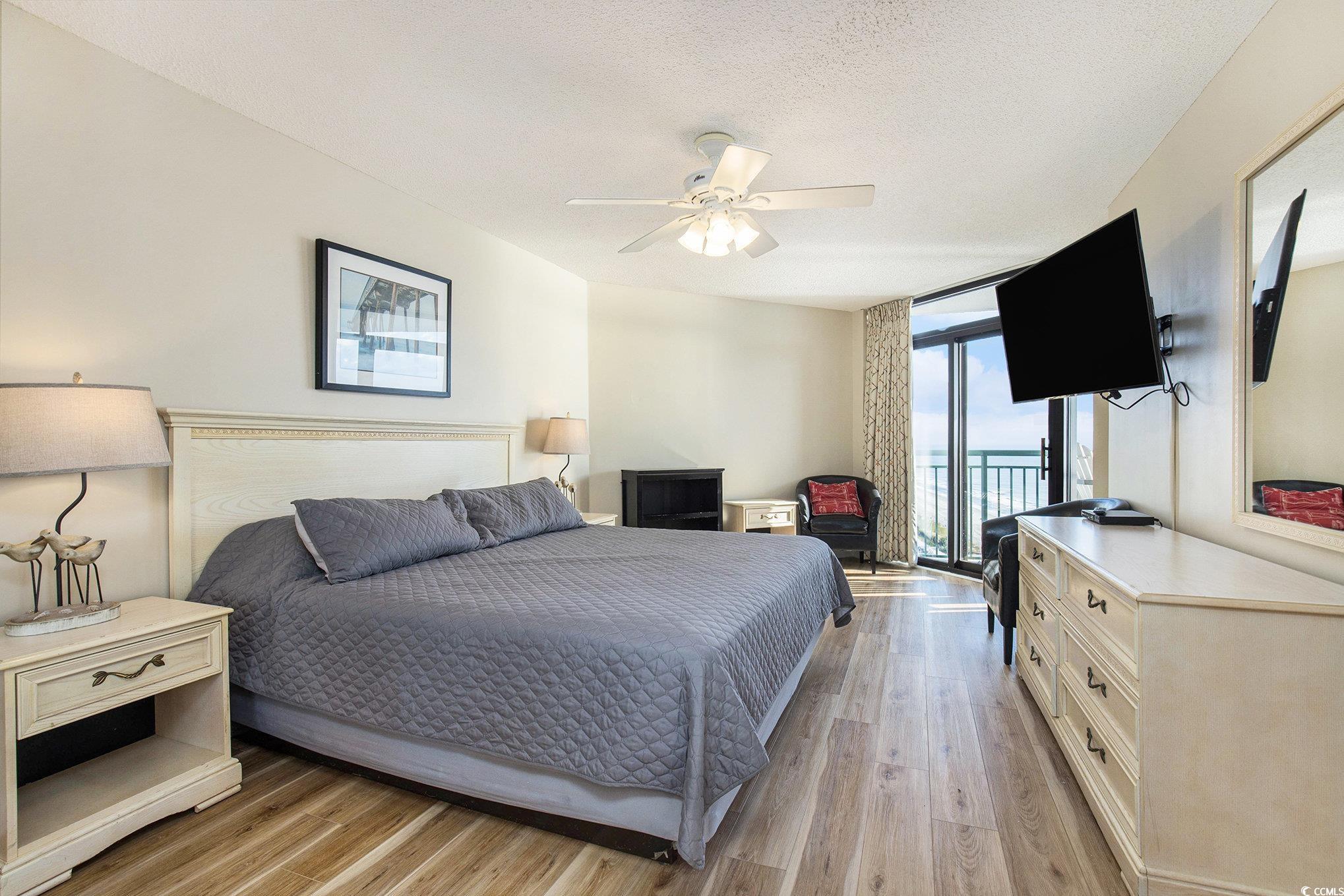 205 74th Avenue North, Unit 1810 Myrtle Beach, SC 29572 - Photo 26 of 37 Bedroom featuring expansive windows, access to exterior, light wood-style floors, a ceiling fan, and a textured ceiling