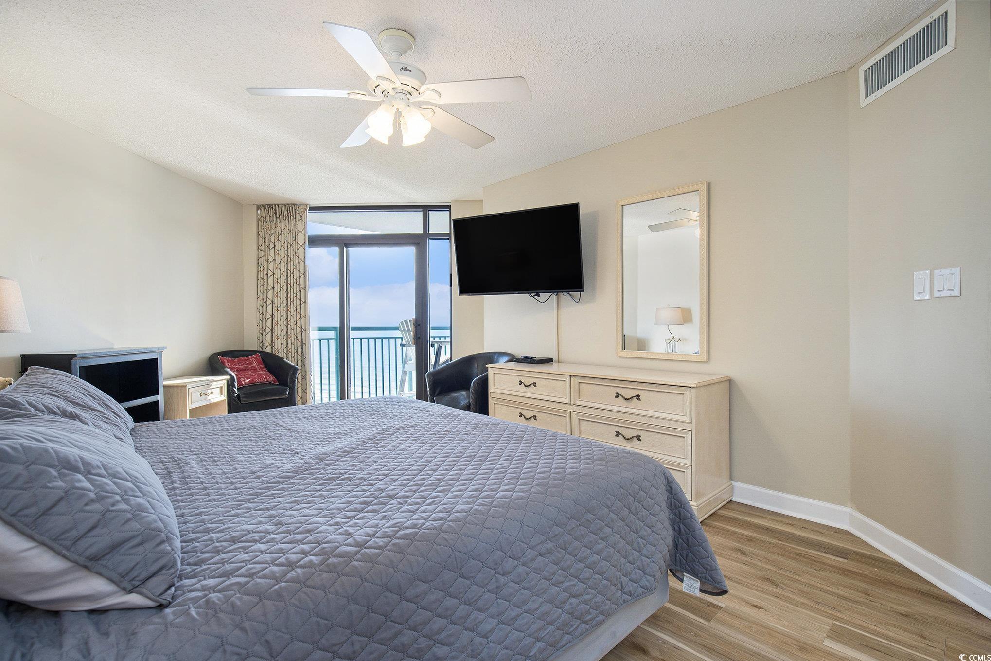 205 74th Avenue North, Unit 1810 Myrtle Beach, SC 29572 - Photo 27 of 37 Bedroom featuring expansive windows, light wood-type flooring, access to exterior, a textured ceiling, and a ceiling fan