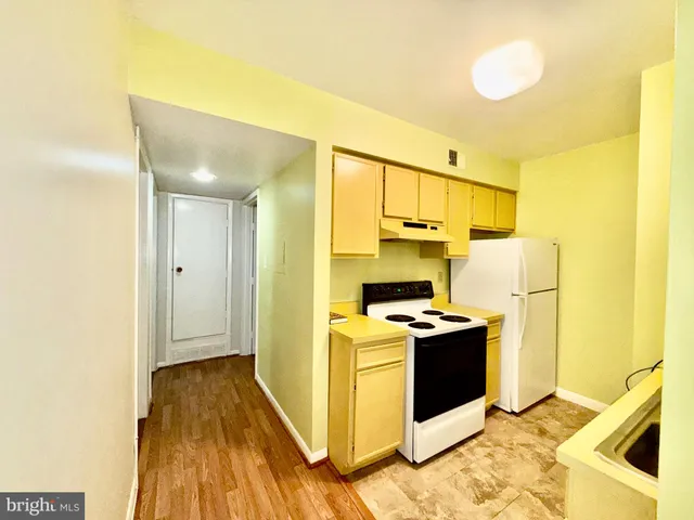 a kitchen with a stove a refrigerator and wooden floor