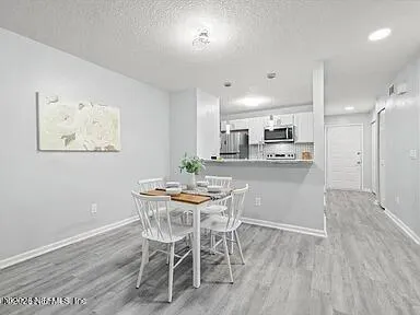 a kitchen with kitchen island a dining table chairs cabinets and wooden floor